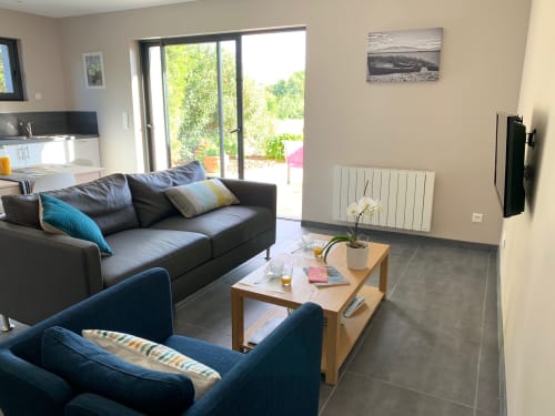 Modern living room in Cottage L'Olivier at Gites Mas D'en Ratéro, Thuir with dark sofas, wooden coffee table, and garden view