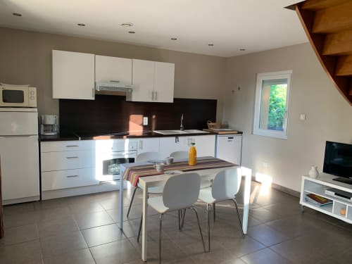 Modern cottage kitchen and dining area at Gites Mas D'en Ratéro in Thuir with white cabinets, black backsplash, and dining