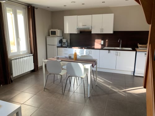 Modern kitchen and dining area in Cottage Força Réal at Gites Mas D'en Ratéro, Thuir with white cabinets, black countertop,