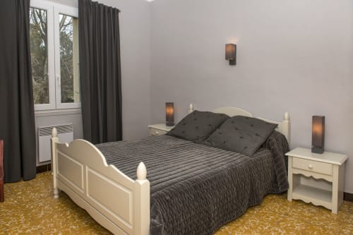 Bedroom in Cottage L'Arbousier at Gites Mas D'en Ratéro, Thuir, featuring cream bed frame with dark bedding, nightstands, and