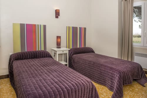 Twin beds with purple quilts in Cottage L'Arbousier at Gites Mas D'en Ratéro, Thuir, featuring colorful striped artwork and