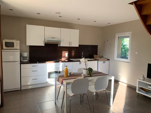 Cuisine-salle à manger moderne aux Gites Mas D'en Ratéro à Thuir avec armoires blanches, plan de travail noir et table à manger