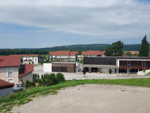Le Comtois BnB en Saône avec cour contemporaine, bâtiments aux toits rouges et collines ondulantes en arrière-plan