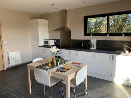 Cuisine et salle à manger modernes aux Gîtes Mas D'en Ratéro à Thuir avec armoires blanches et plan de travail noir