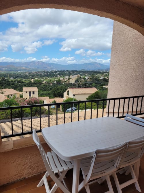 Vue de balcon de l'appartement de Porticcio en Corse avec table à manger, surplombant la vallée et les montagnes
