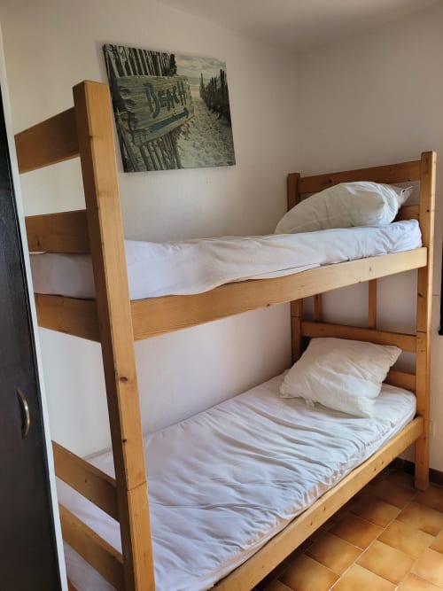 Lits superposés en bois avec draps blancs dans un appartement corse à Porticcio, décor balnéaire
