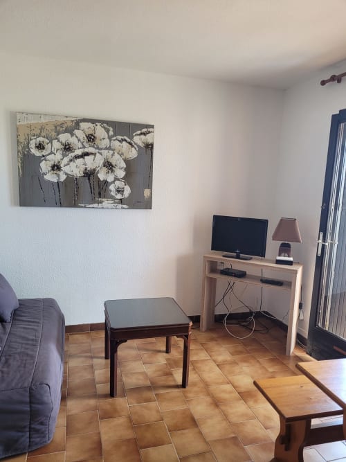 Salon douillet d'un appartement corse avec téléviseur, coin salon et décoration florale blanche à Porticcio