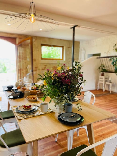 Elegant dining room at Maison Monsieur Léger with set table, fresh flowers, and modern pendant light in Montaut