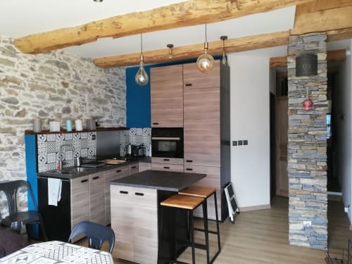Modern kitchen with wooden beams, stone walls, and dining area in Aime la Plagne cottage rental.
