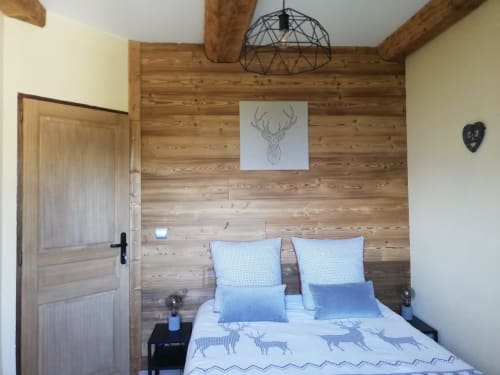 Cozy bedroom at La Maison De L'Épine cottage with wooden beams, deer artwork, and blue bedding in Aime la Plagne
