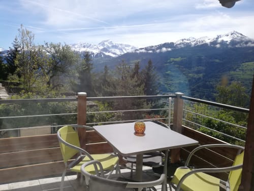 Alpine terrace with yellow chairs overlooking snow-capped mountains at La Maison De L'Épine, Aime la Plagne