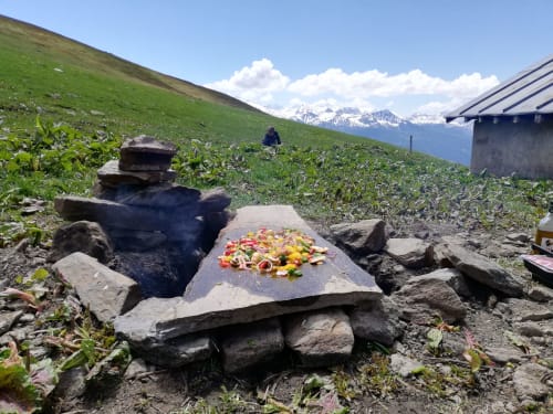 Alpine picnic shrine with colorful flowers at La Maison De L'Épine, Aime la Plagne, with snowy mountains and green meadows