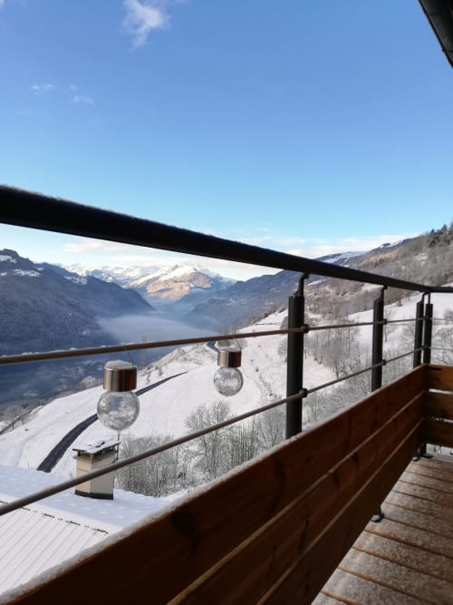 Snowy mountain balcony view overlooking alpine lake and peaks at La Maison De L'Épine, Aime la Plagne