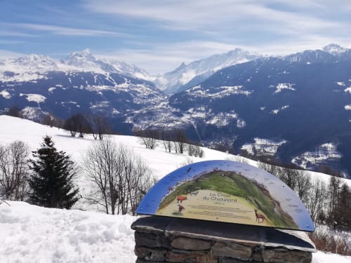 Snow-covered Alpine landscape with interpretive sign at La Croix du Chatelard, Aime la Plagne, mountains beyond