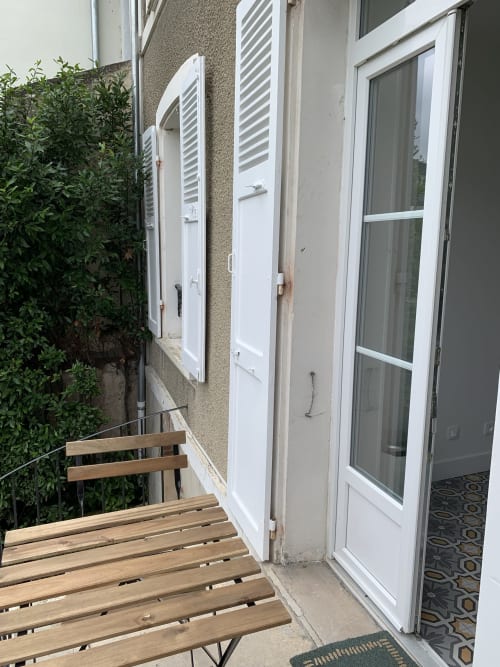 Terrasse extérieure avec banc en bois et fenêtres aux volets blancs aux Remparts de Joussaume, chambres d'hôtes à Château-Thierry