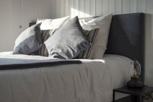 Modern bedroom at Chalet Domisiladoré with neatly arranged pillows, white bedding, and dark headboard in French Alps