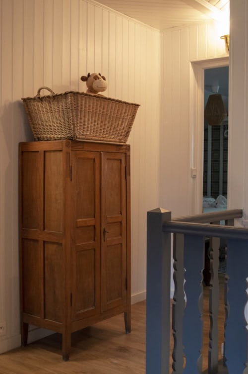 Wooden cabinet with wicker basket and teddy bear in Chalet Domisiladoré hallway, French Alps