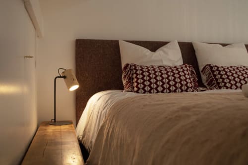 Cozy bedroom at Chalet Domisiladoré with brown upholstered headboard, patterned pillows, and bedside lamp