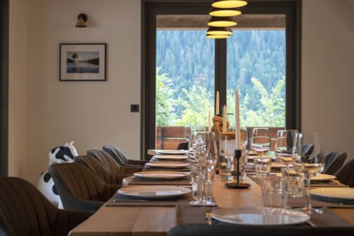 Modern dining room at Chalet Domisiladoré with mountain views, set table, and pendant lighting