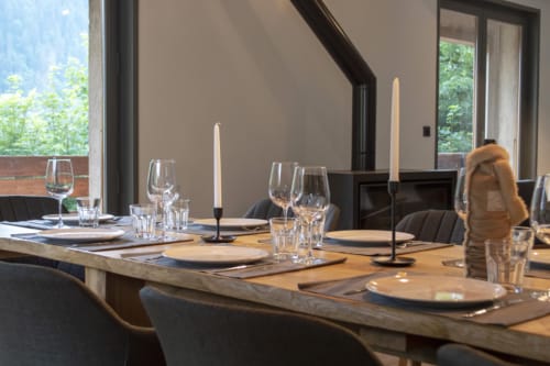Elegant dining room at Chalet Domisiladoré with set table, candlesticks, glassware, and mountain views through windows