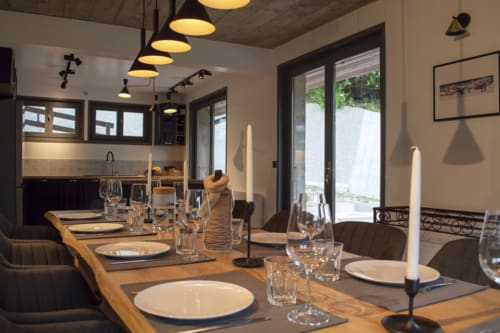 Elegant dining room at Chalet Domisiladoré with wooden table, place settings, pendant lights, and glass doors opening to
