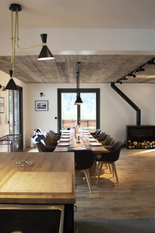 Modern dining room at Chalet Domisiladoré with long table, black chairs, pendant lights, and fireplace