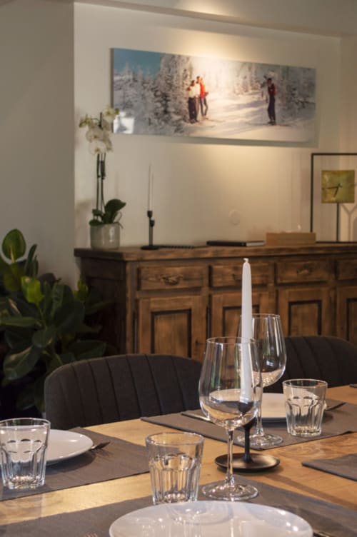 Elegant dining room at Chalet Domisiladoré with place settings, winter mountain artwork, and wood sideboard with decor.