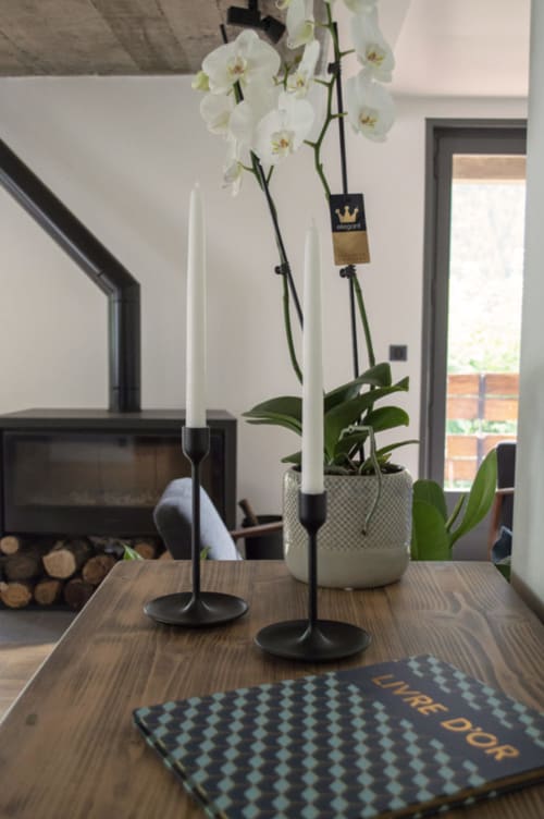White orchids in ceramic pot with black candlesticks on wooden table at Chalet Domisiladoré