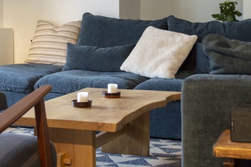 Cozy living room at Chalet Domisiladoré with blue sectional sofa, wooden coffee table with candles, and decorative pillows
