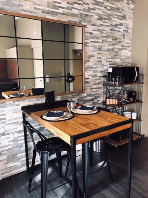 Espace repas moderne du Love and Spa B&B à Meynes avec table en bois, chaises noires et mur en brique