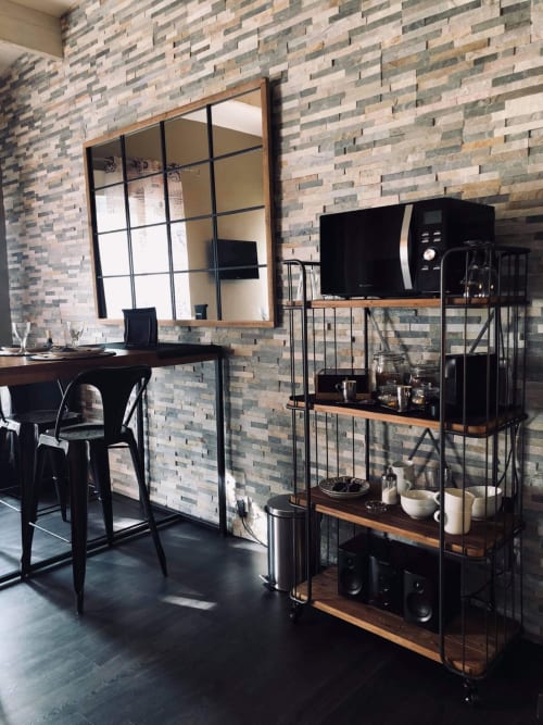 Kitchenette moderne avec mur en briques, comptoir noir, miroir et étagères industrielles à l'hôtel Love and Spa, Meynes
