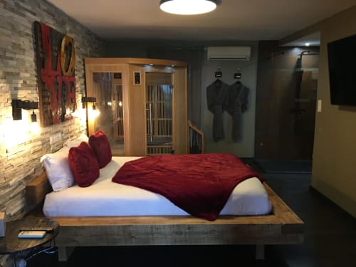 Chambre Modern Love and Spa à Meynes avec literie rouge, mur en briques, lit en bois et équipements spa