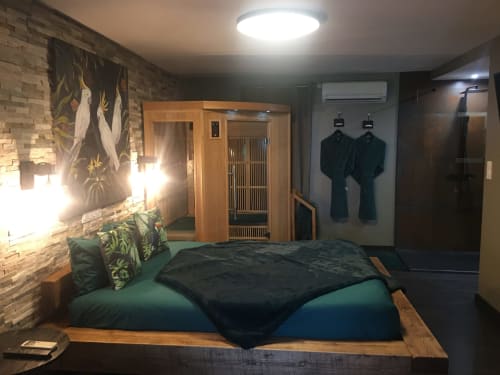 Chambre Love And Spa à Meynes avec sauna en bois, linge de lit vert, mur de briques et équipements modernes