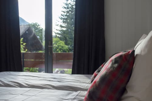Modern bedroom with mountain view balcony at Chalet Domisiladoré, French Alps villa with dark curtains and comfortable