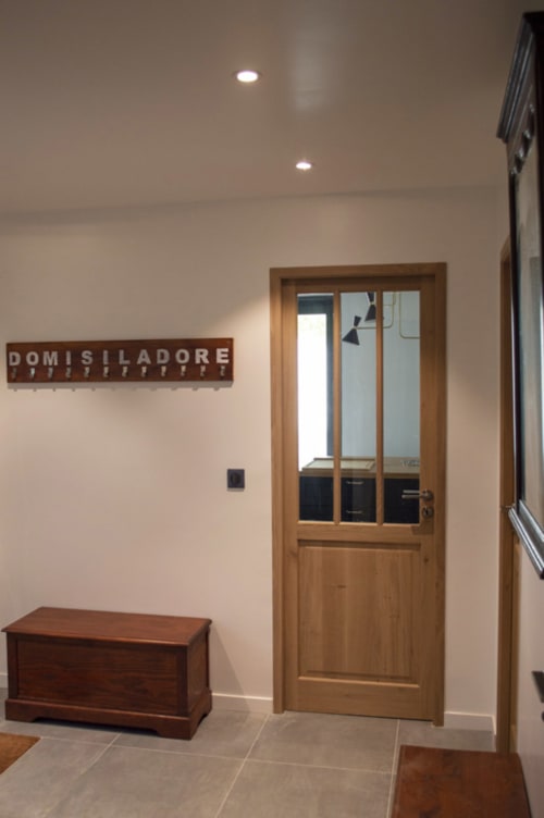 Chalet Domisiladoré entrance hallway with wooden door, bench, and signage in French Alps villa