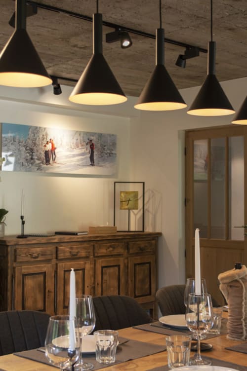 Modern dining area at Chalet Domisiladoré with black pendant lights, wooden furniture, and mountain view artwork on walls