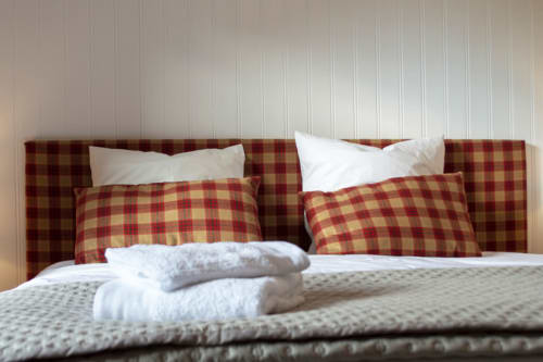 Cozy bedroom at Chalet Domisiladoré with red plaid headboard, white pillows, and folded towels on bed