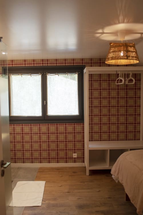 Cozy bedroom at Chalet Domisiladoré with plaid wallpaper, wooden floors, pendant lighting, and modern furnishings