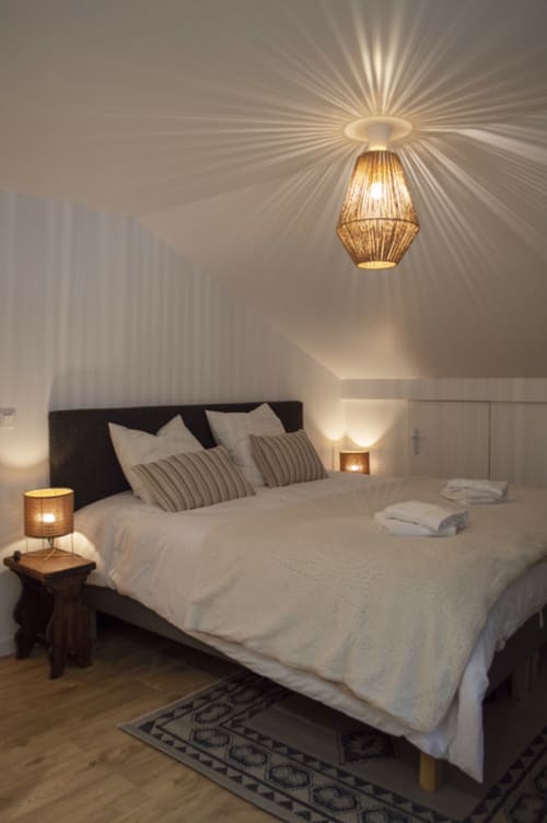 Elegant bedroom at Chalet Domisiladoré with pendant light, black bed, striped pillows, and ambient lighting