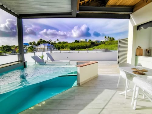 Luxurious pool deck at Habitation I'SEO in Sainte-Anne, Guadeloupe with turquoise pool, lounge chairs, and ocean views