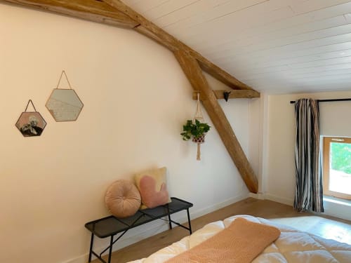 Chambre mansardée douillette à la Maison Monsieur Léger à Montaut : poutres en bois, miroirs hexagonaux, plante suspendue et banc noir