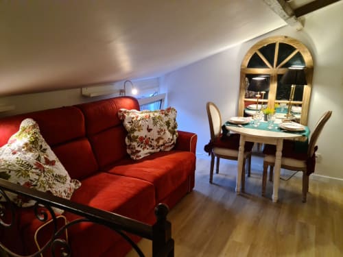 Le Studio cottage du Petit Nid d'Aigle à Giverny avec canapé rouge, coin repas et vue sur le jardin.