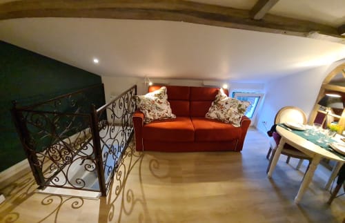 Espace lounge contemporain du Studio au Petit Nid d'Aigle à Giverny, avec canapé rouge-rouille, coussins décor et mobilier raffiné
