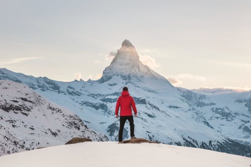 Hiker in red jacket overlooking snow-covered Matterhorn, Chalet Domisiladoré, French Alps