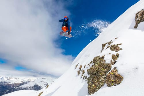 Skieur en veste orange décollant d'une pente enneigée près du Chalet Domisiladoré, Alpes françaises