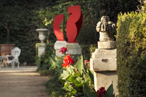 Sculpture de jardin du Mas de Lafeuillade avec installation artistique rouge, topiaire de haie et fleurs rouges à Montpellier