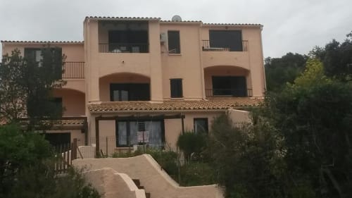 Immeuble d'habitation couleur terre cuite à Porticcio, Corse avec balcons, vue sur la mer et végétation méditerranéenne
