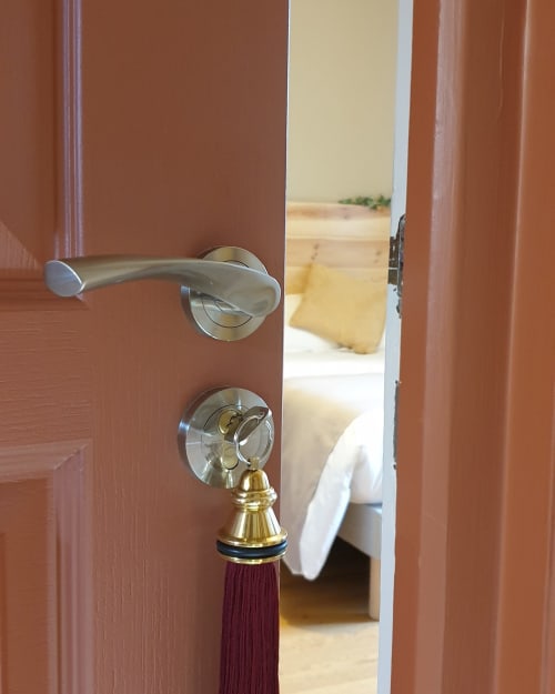 Porte en bois ouverte du Château de Grandmont B&B à Blacé révélant une chambre avec lit et oreiller jaune