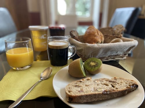 Petit-déjeuner au Château de Grandmont avec croissants, pain, kiwi, jus d'orange et café