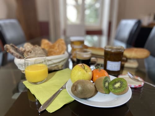Petit-déjeuner gourmand au Château de Grandmont à Blacé : fruits frais, jus, pain, viennoiseries et confitures sur la table